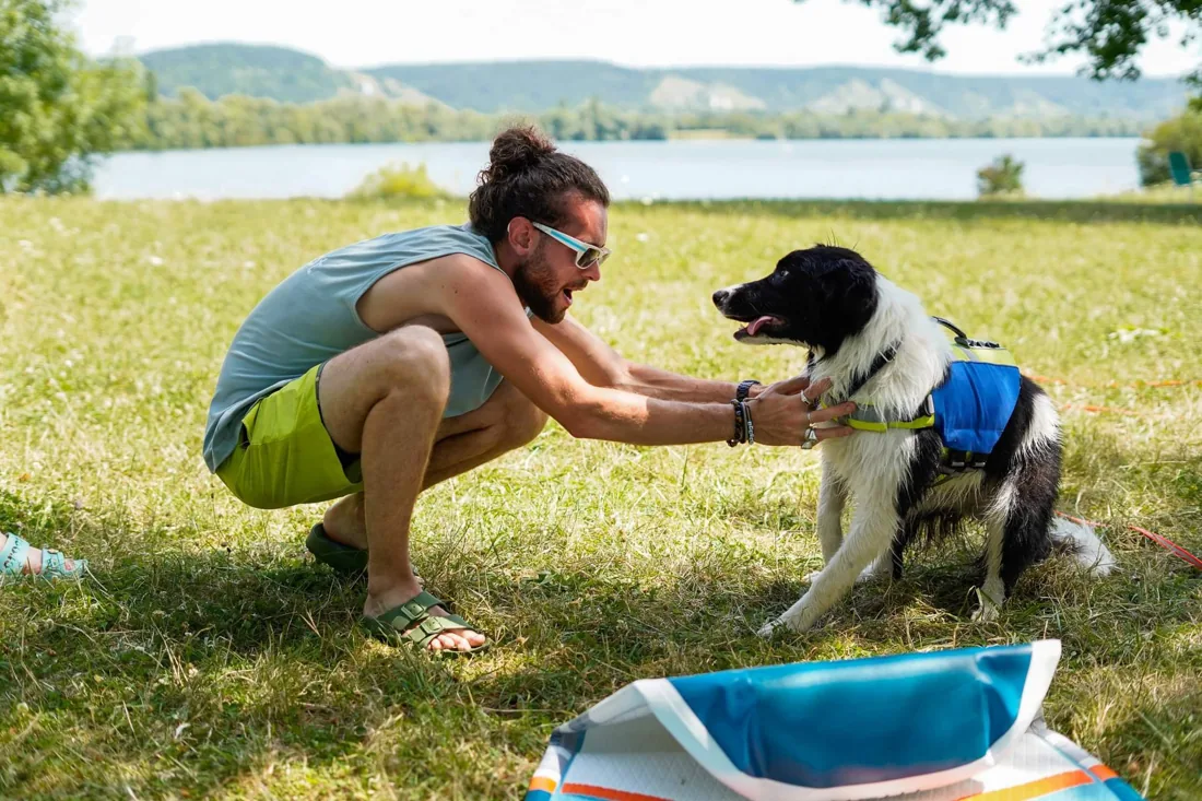 Complicité entre un maître et son chien au bord du lac avant une sortie cani-paddle